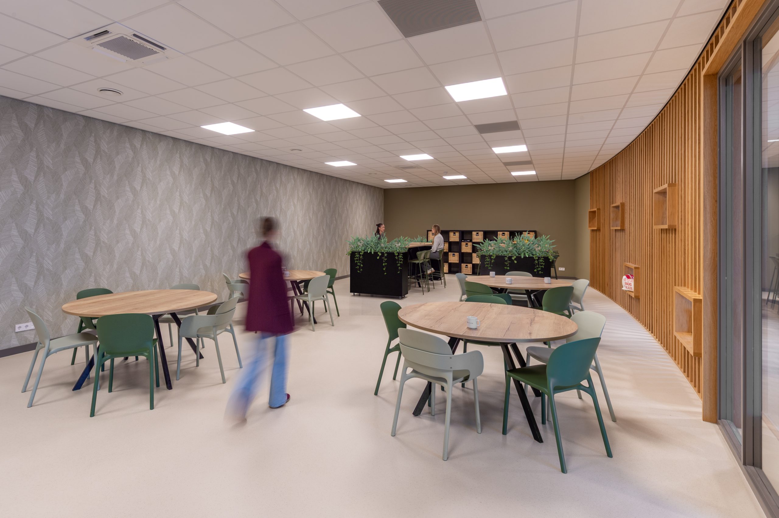 Lichte kantine met groene stoelen en houten wand bij Piet de Wit Snacks